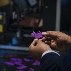 Hands holding 3-D printed purple Scottie dog