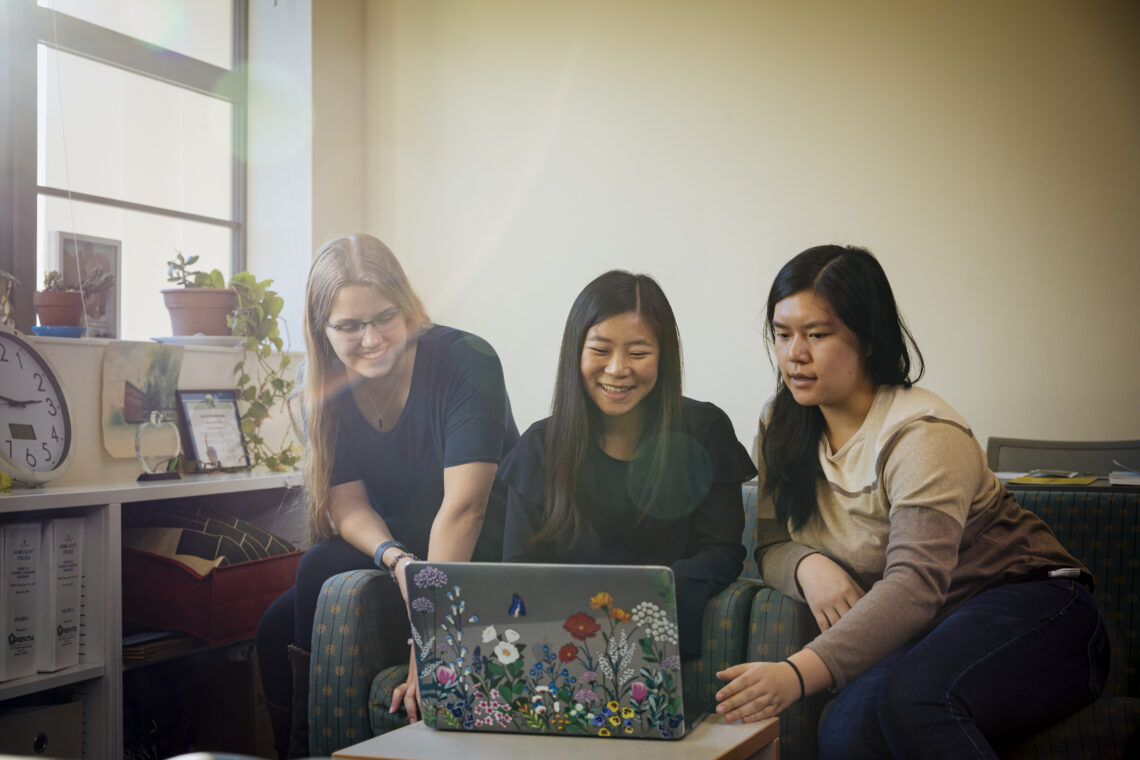 Three students gather around a computer.