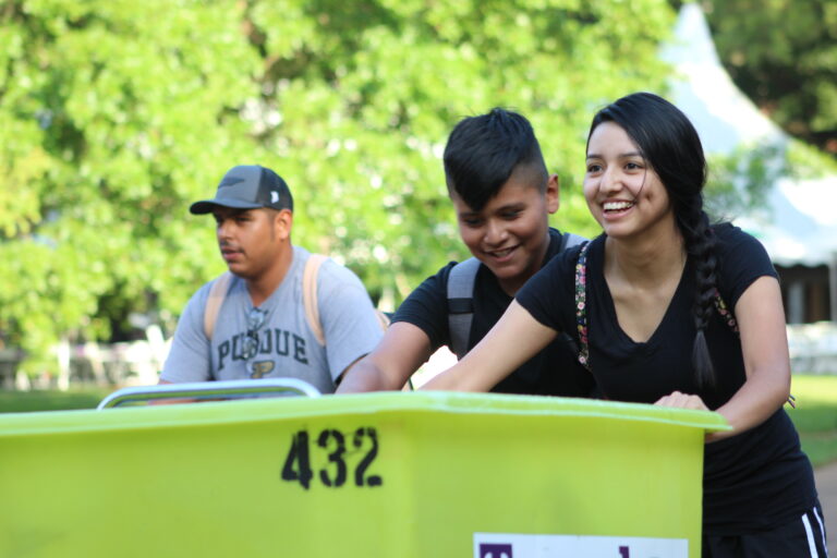 Student smiles while pushing a bin.