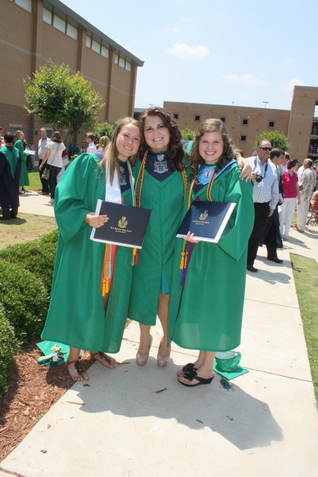 Three girls wearing green caps and gowns