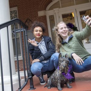 Two students take a selfie with statue of a Scottie dog, Ramona