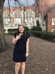 Student standing on campus holding up black onyx ring