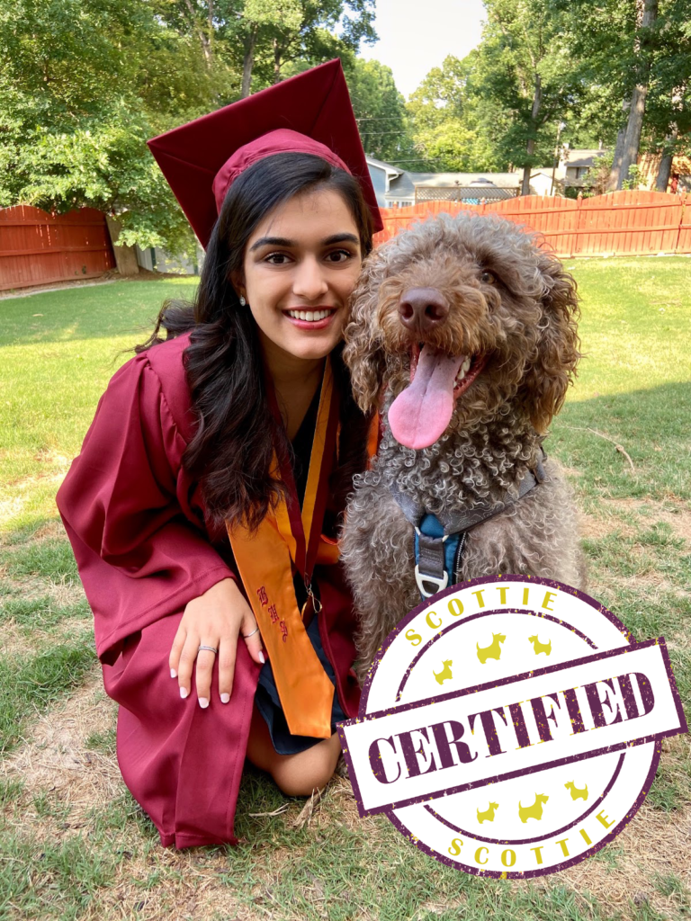 Inaara Vadsaria wearing red graduation robe with a dog