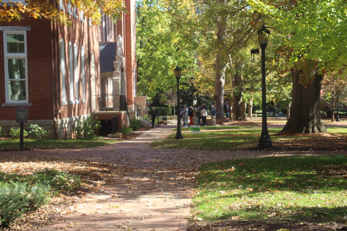 Campus walkway in fall- a tour group stands in distance