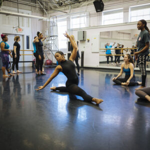 Students in a dance class watch one student, who is dancing.