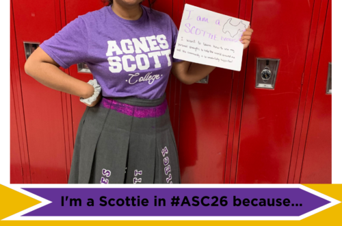 Anjali David wearing an Agnes Scott shirt holding a sign. Text reads: "I'm a Scottie in #ASC26 because I want to learn how to use my personal strengths to help the world around me, and the community is so wonderfully supportive!"
