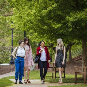 Three students and a professor walk on campus