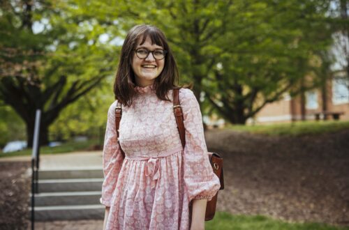 Student wearing pink dress smiles at camera.
