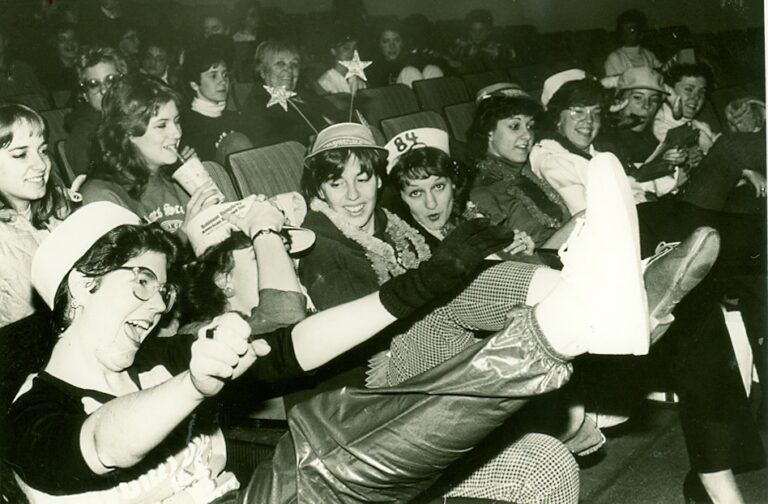Students in costume sit in the audience.