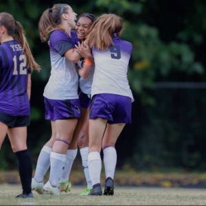Three Agnes Scott soccer players celebrate during a game.