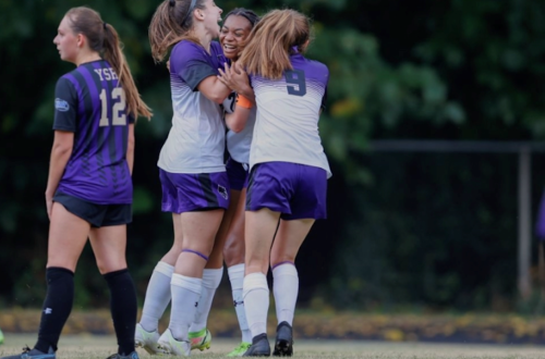 Three Agnes Scott soccer players celebrate during a game.