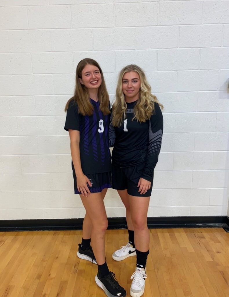 Two athletes pose in uniforms.
