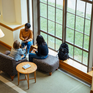 Three Agnes Scott students chat over books in the library.