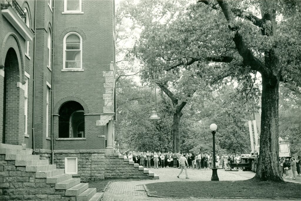 Black and white photo of students congregating at the ringing of the bell.