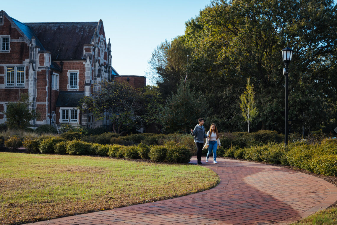 Two students walk down a winding brick path next to Rebekah Scott Hall.