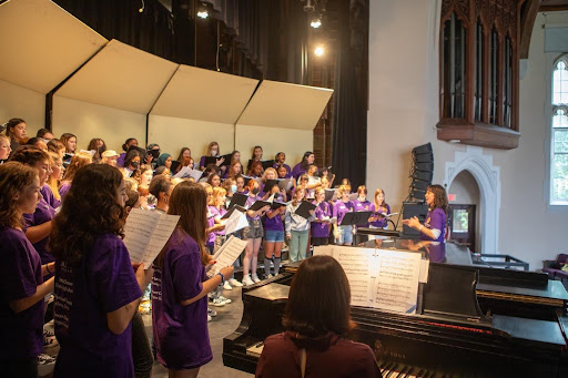 Collegiate Chorale and camp participants in purple tee-shirts sing in Gaines Auditorium.