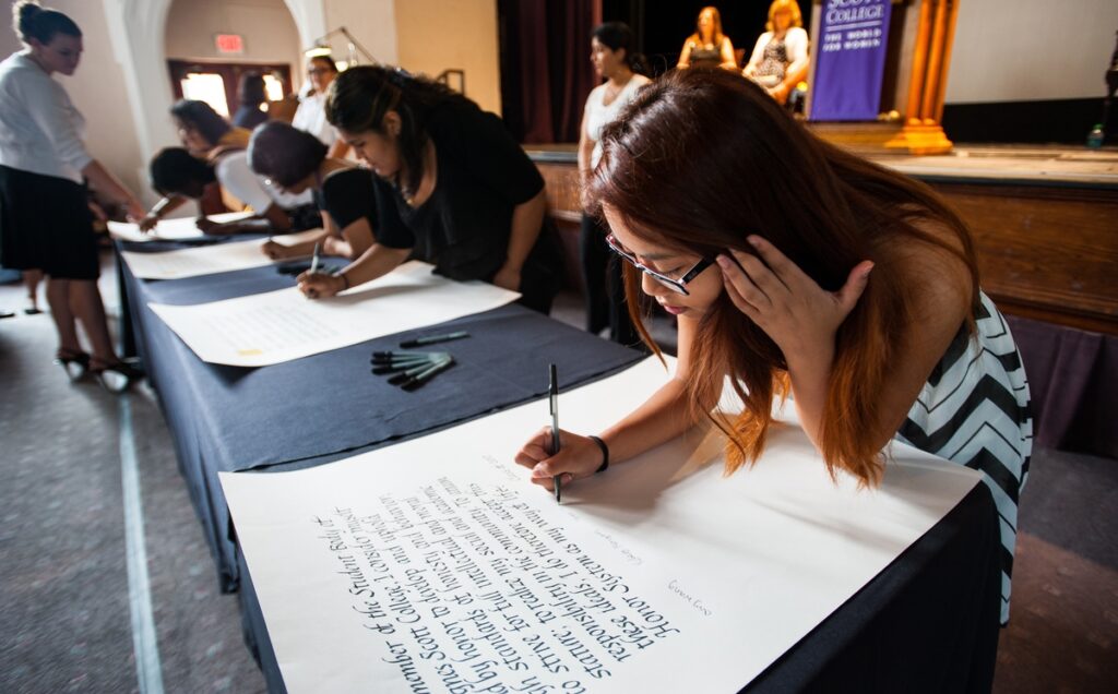 A student holds back her hair while she signs the Agnes Scott honor code